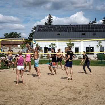 Młodzież grająca w siatkówkę plażową na terenie folwarku matecznik