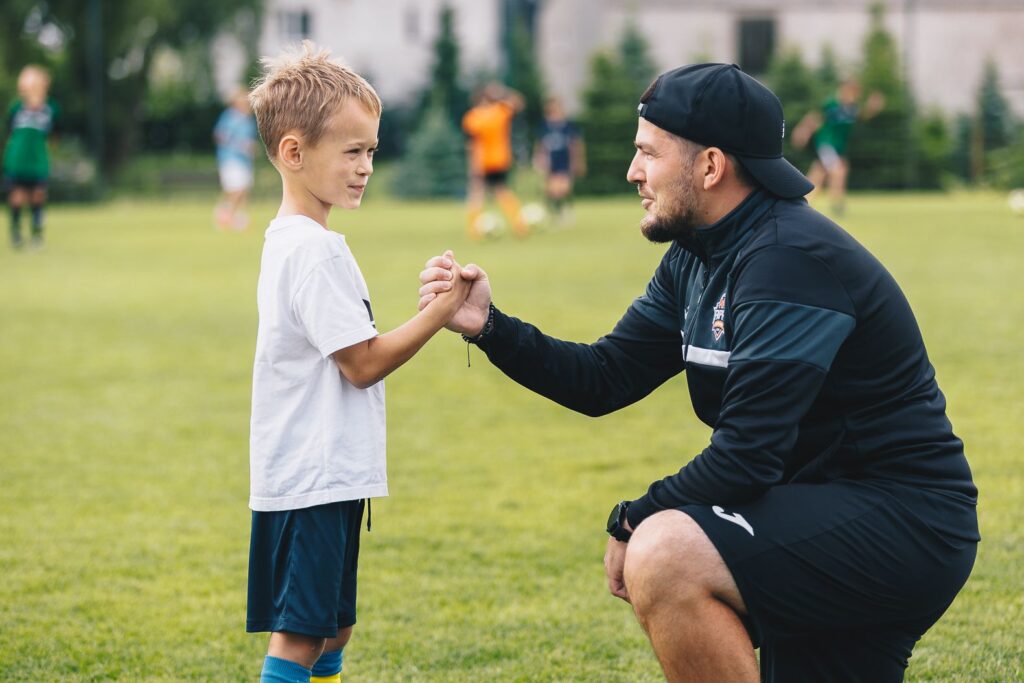 dziecko z trenerem na obocie piłkarskim